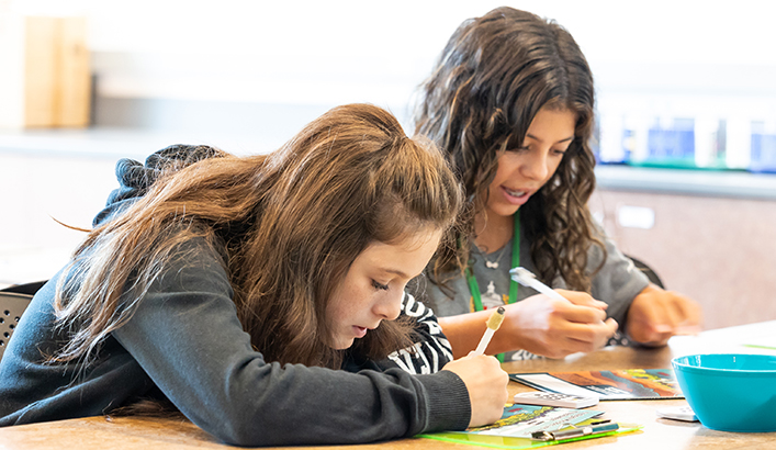 Two girls filling in a worksheet at the WET Science Center.