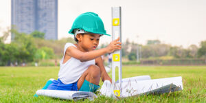 Girl on the grass wearing a hard had and holding a level