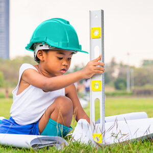 Girl on the grass wearing a hard had and holding a level