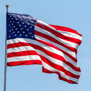 American flag waving on pole with bright vibrant red white and blue colors against blue sky