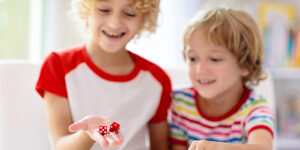 Two children playing with a red pair of dice
