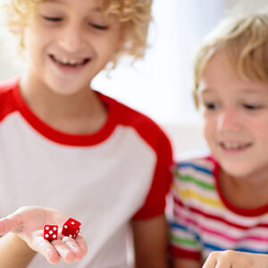 Two children playing with a red pair of dice