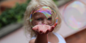 Girl with a soap bubble in her hand holding it up to the camera