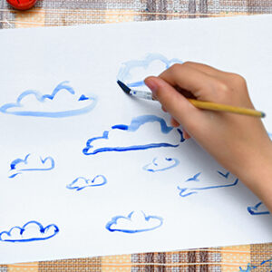 a girl drawing watercolor blue clouds on a blank white paper, artistic creation at home, makes creative artwork