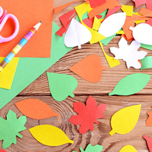 Colored paper sheets, scissors, pencil, autumn colored paper leaves on wooden background. Cutting with scissors. Development of skill for a toddler or preschooler. Top view