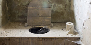 Outhouse toilet with wooden seat and lid open